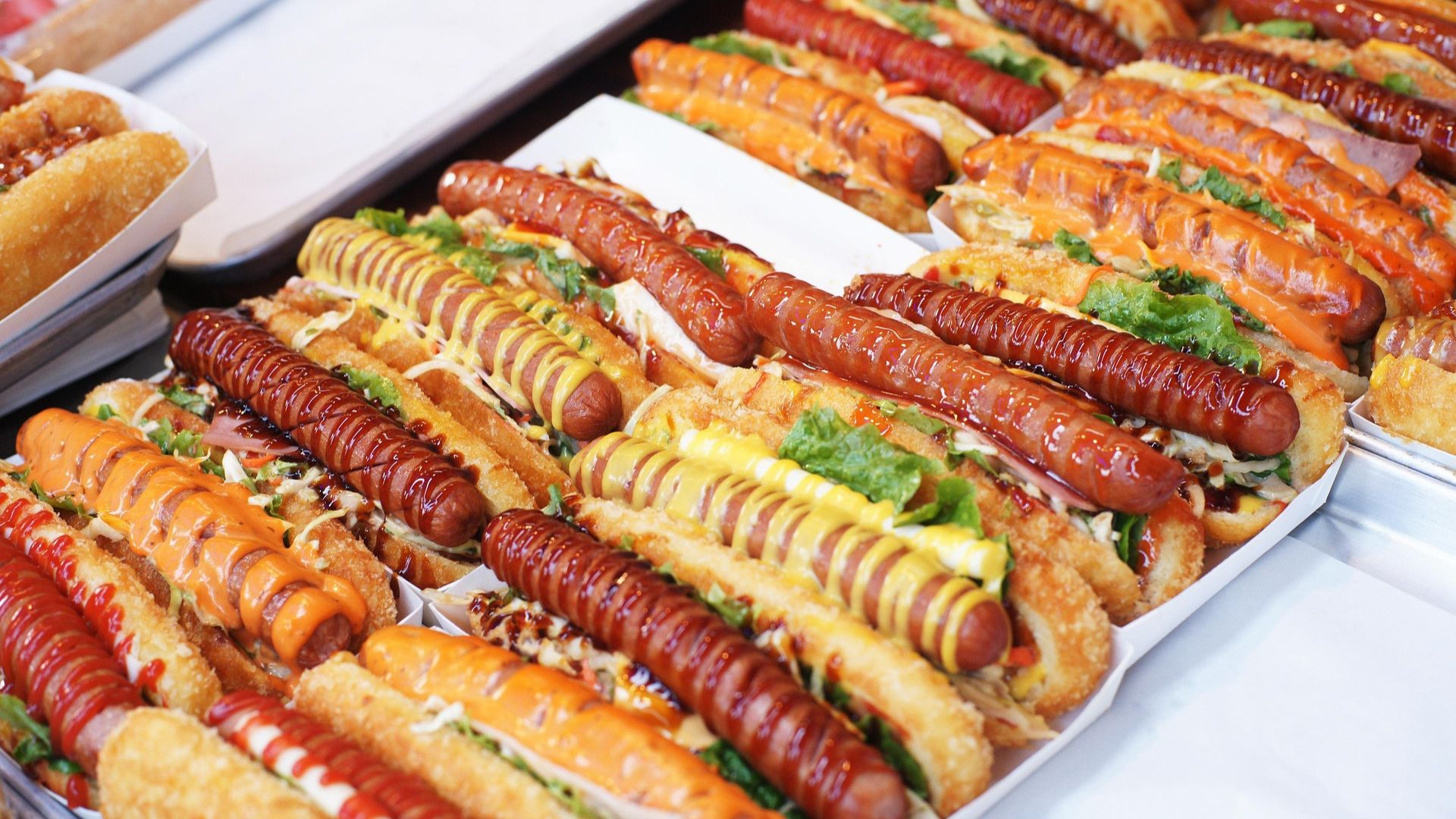 Loaded chili cheese hot dogs topped with sauces and condiments in serving trays