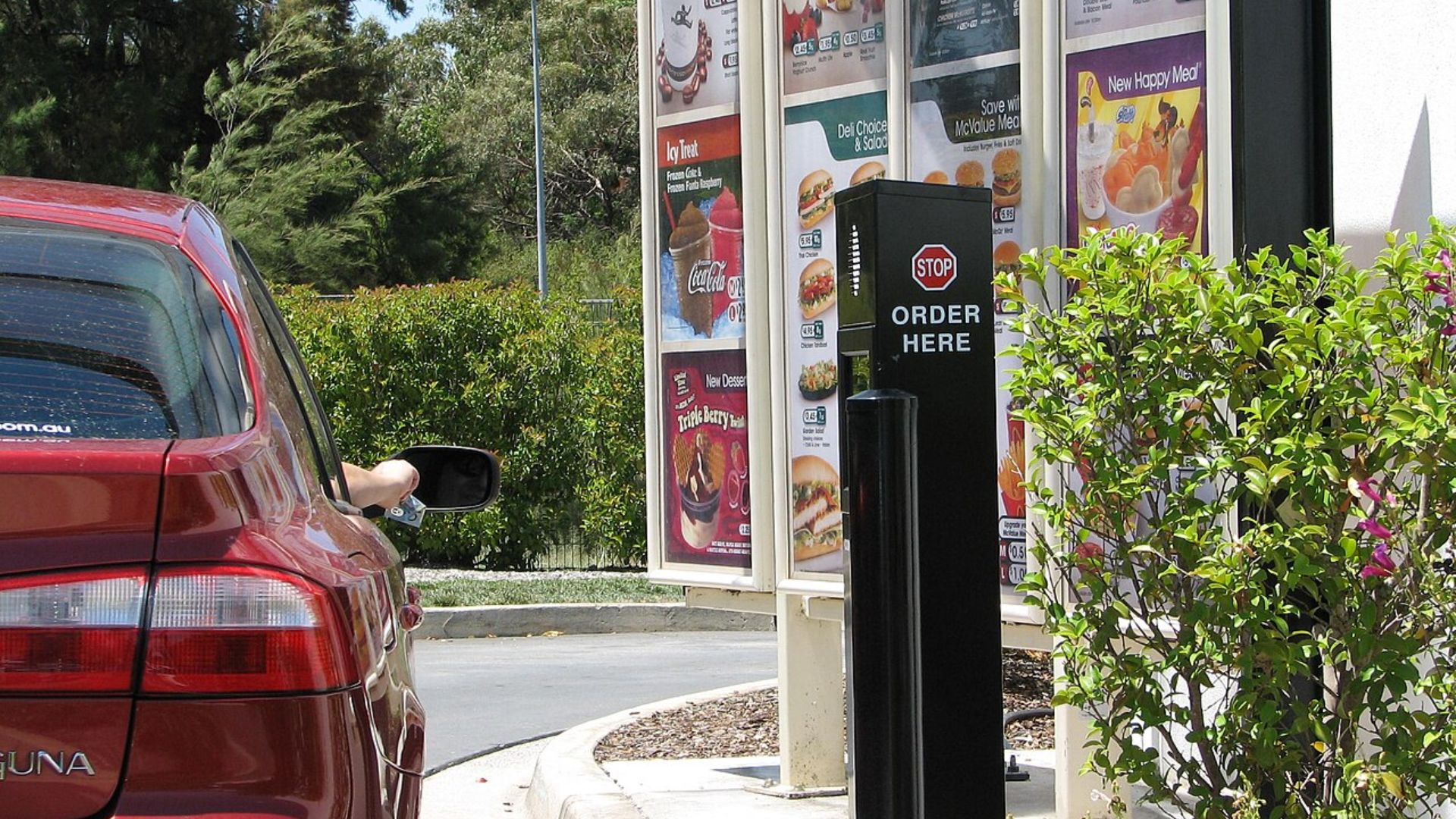 Car at a McDonald’s drive-thru order station beside the menu board.