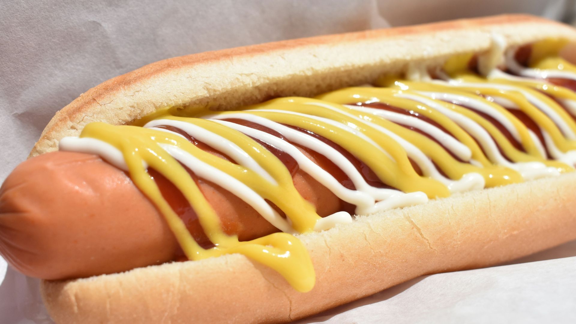 Hot dog in a bun topped with ketchup and mustard condiments