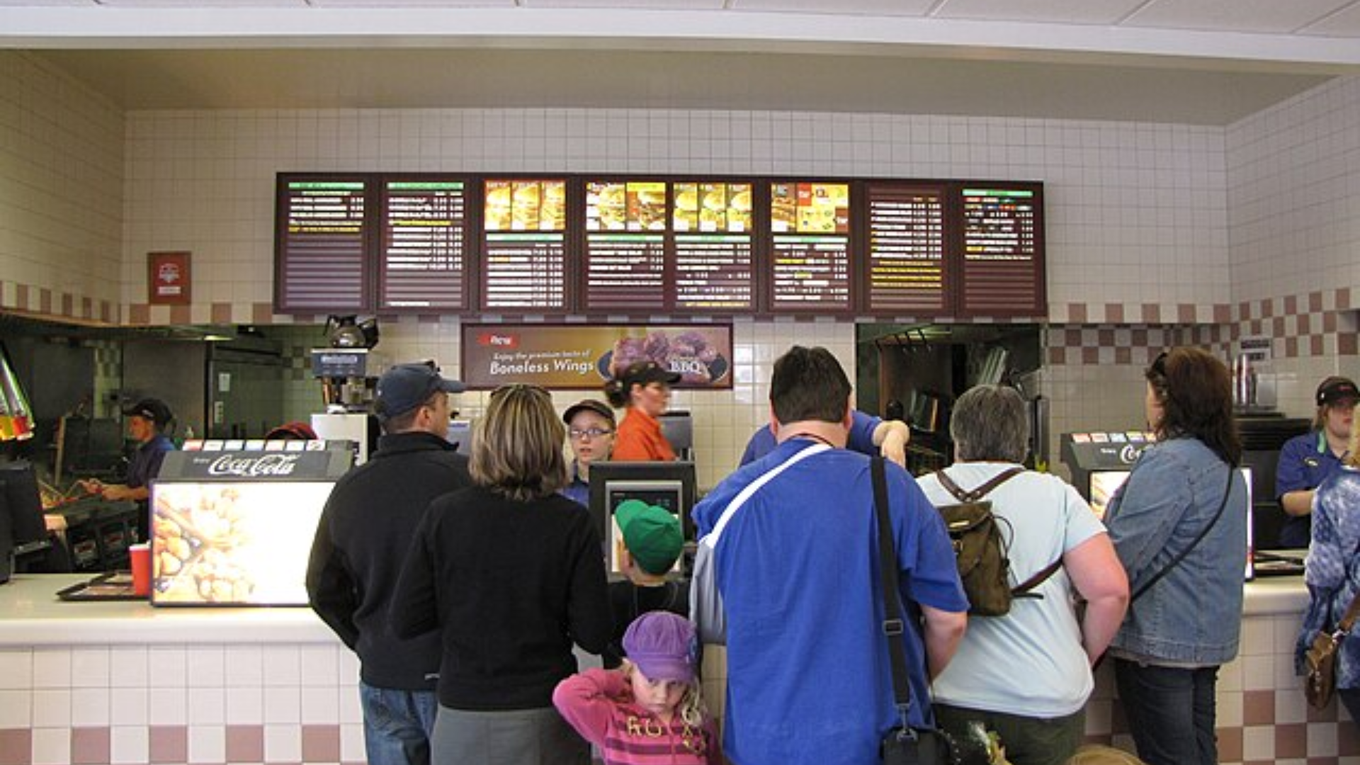 People standing in line to order food at a fast food restaurant.