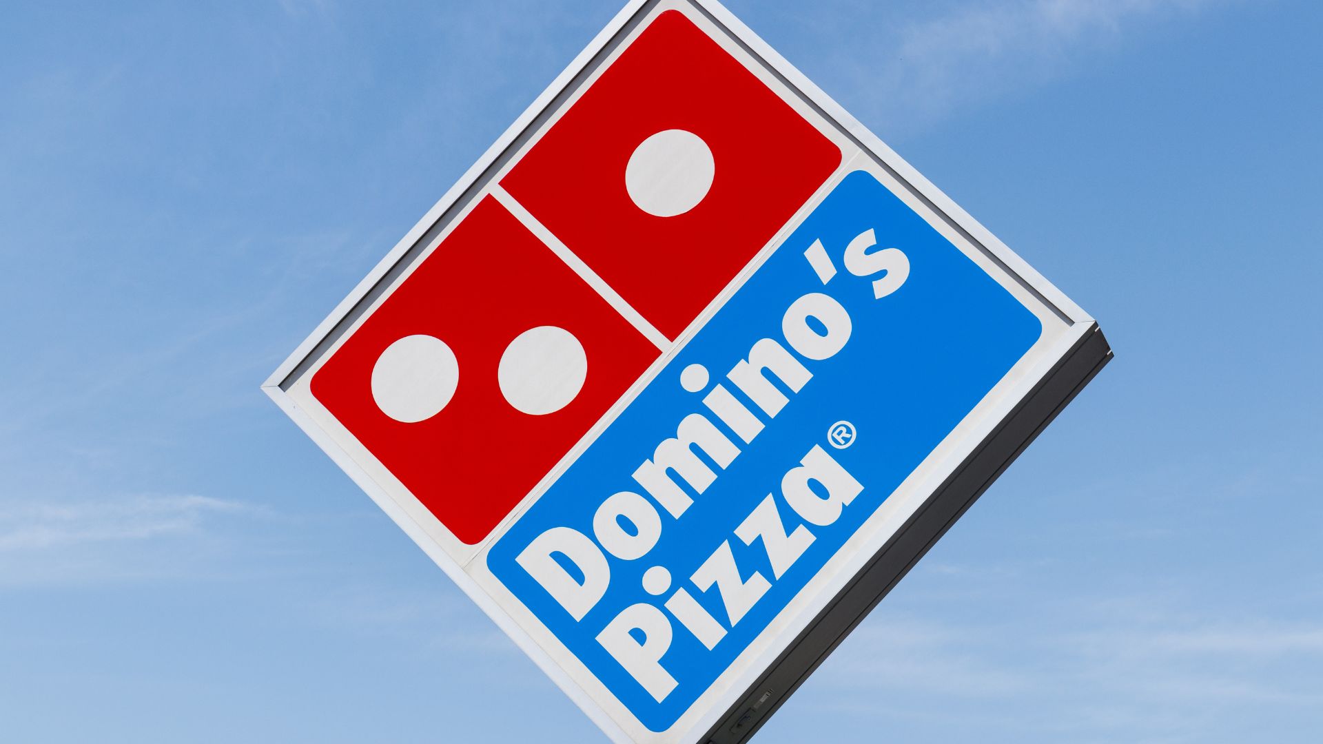 Large Domino’s Pizza sign displayed outside a restaurant location against the sky