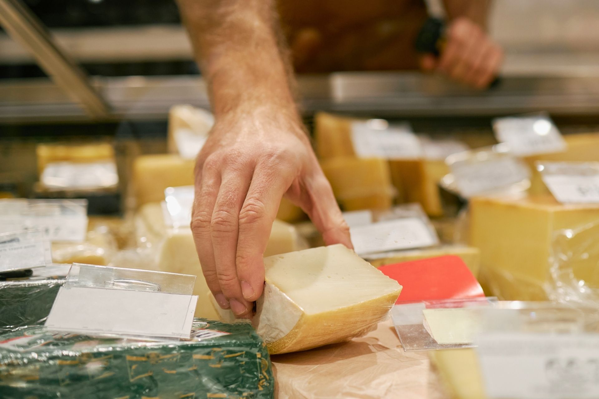 Assorted cheeses displayed at a market counter.