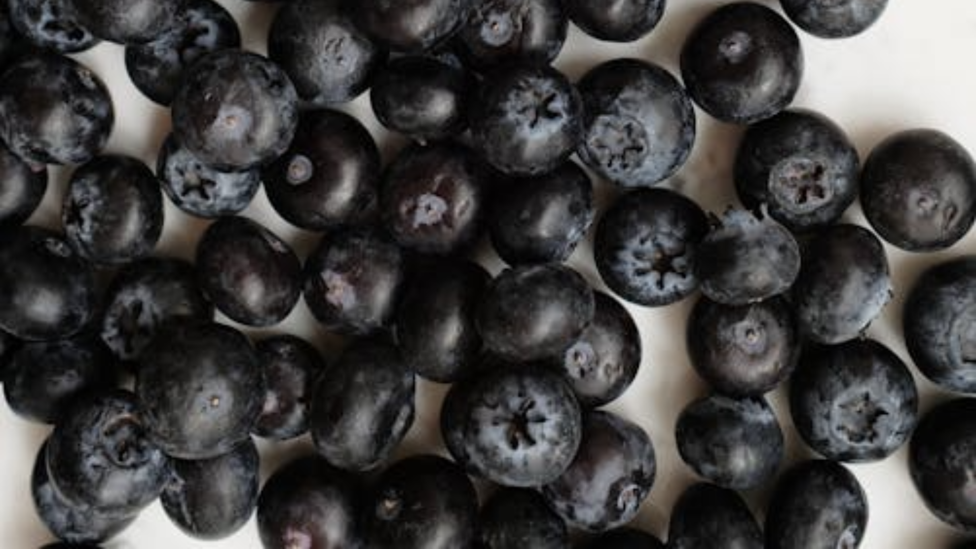 A collection of fresh nightshade berries scattered across a white marble surface.