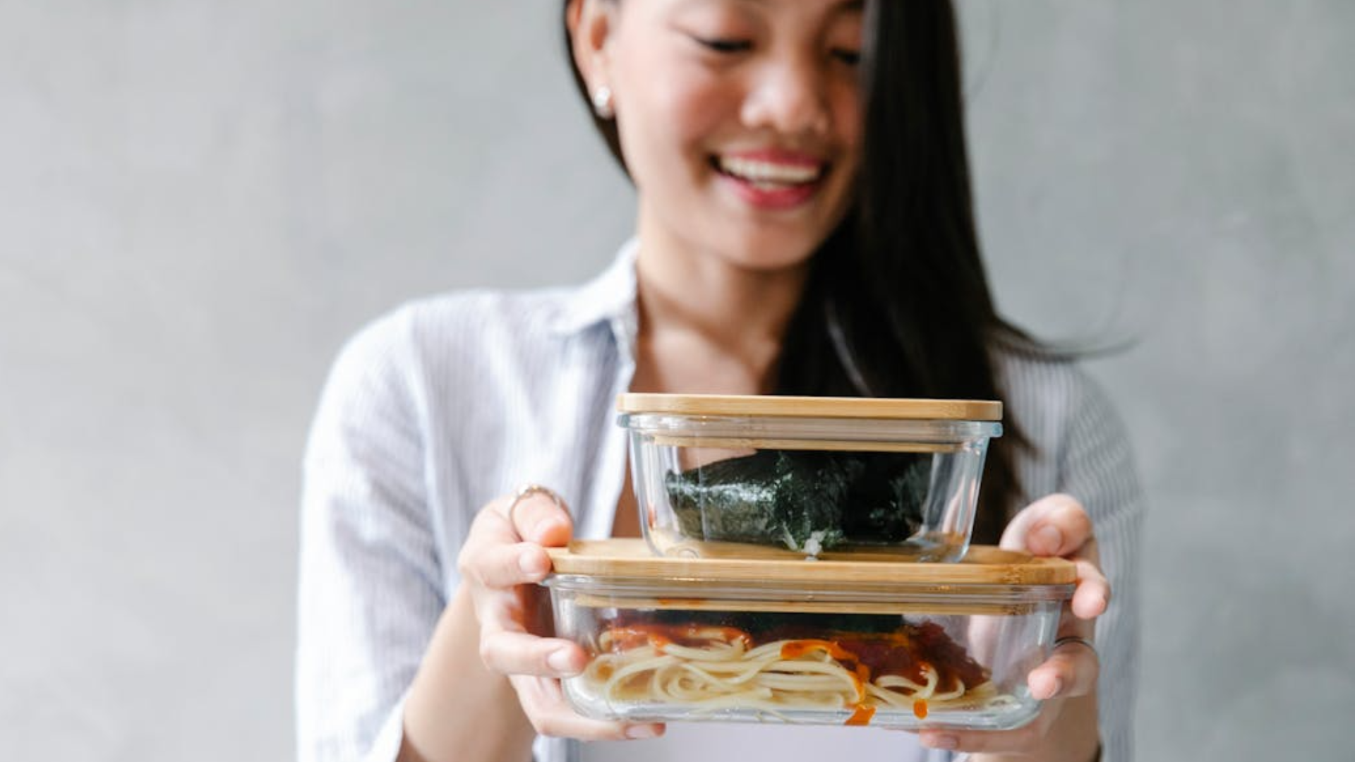 Woman holding a glass container with food in it.