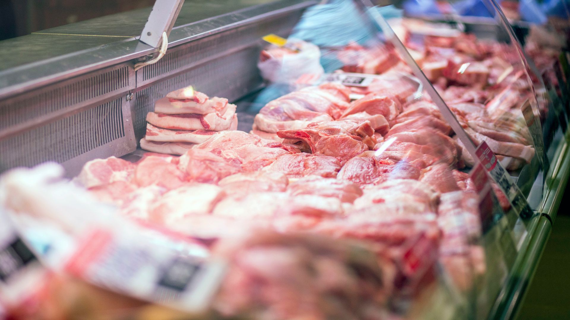 Raw pieces of meat are in the refrigerator with price tags.
