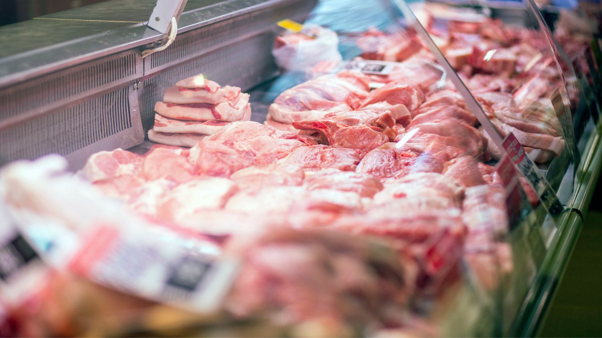 Meat in a refrigerator with price tags ready to be sold in the meat department of the store.