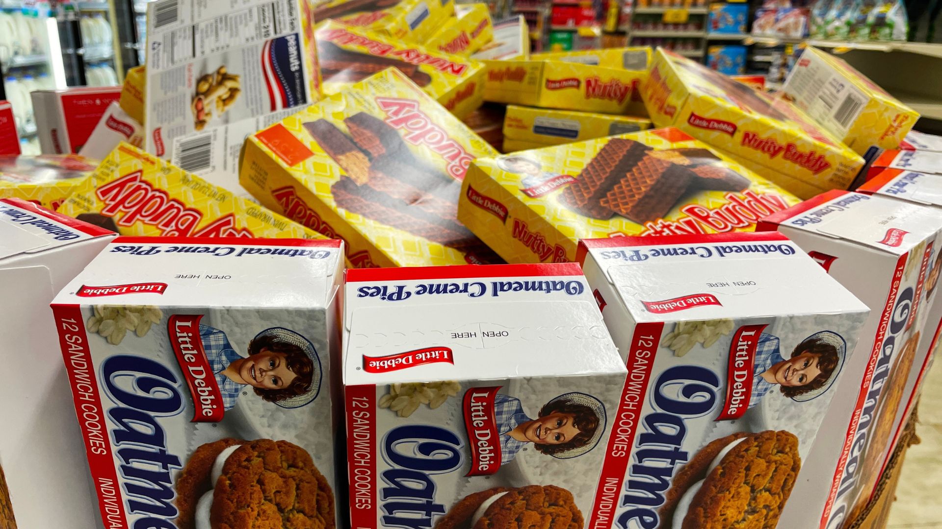 Grocery store Little Debbie snack cakes like Nutty Buddy and Oatmeal Creme Pies stacked on top of each other.