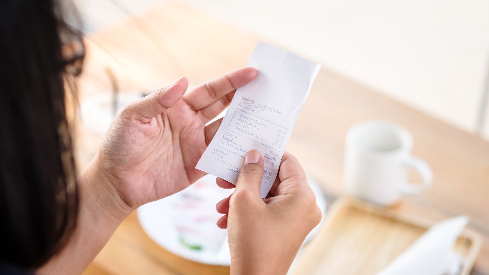 Closeup of a woman checking her bill after a meal at a restaurant.