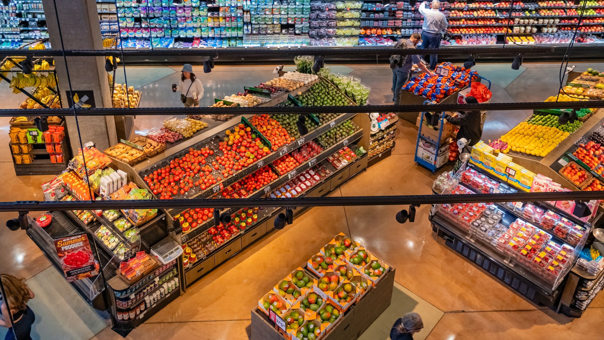 Grocery store shoppers in the vegetable and fresh produce section.