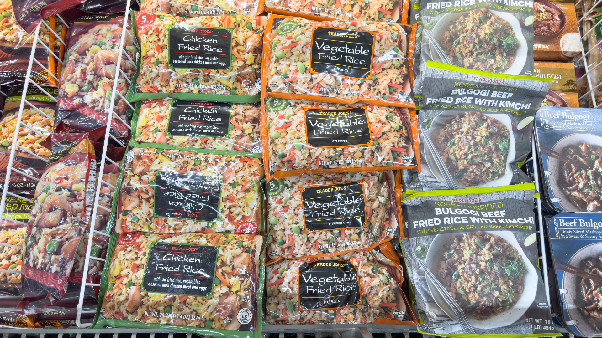 A variety of Trader Joe's frozen fried rice packages, including Chicken, Vegetable, and Bulgogi Beef, displayed in a freezer case.