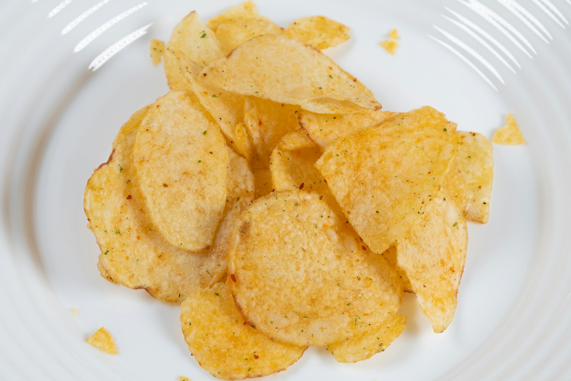 Chips de pommes de terre assaisonnées sur une assiette blanche.
