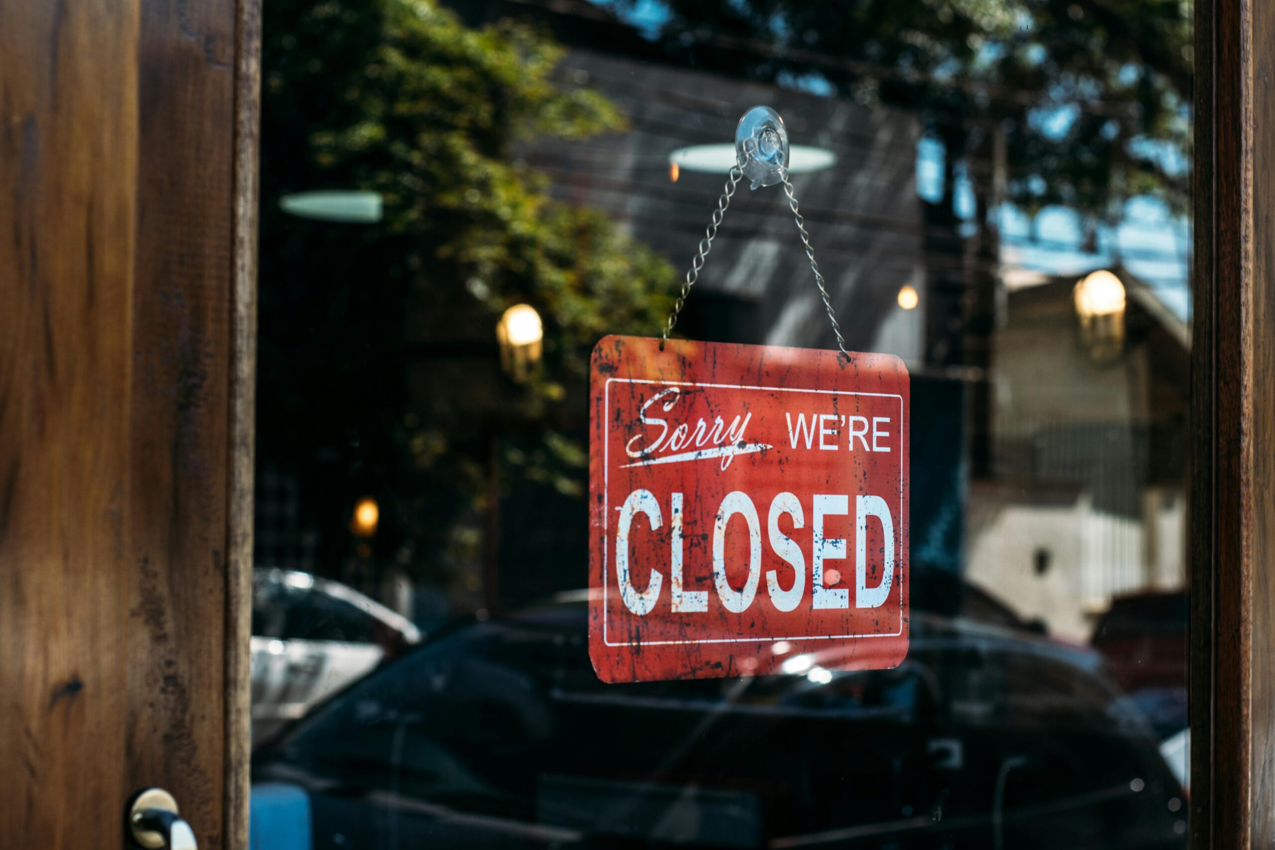 Closed sign hanging on glass door of storefront.