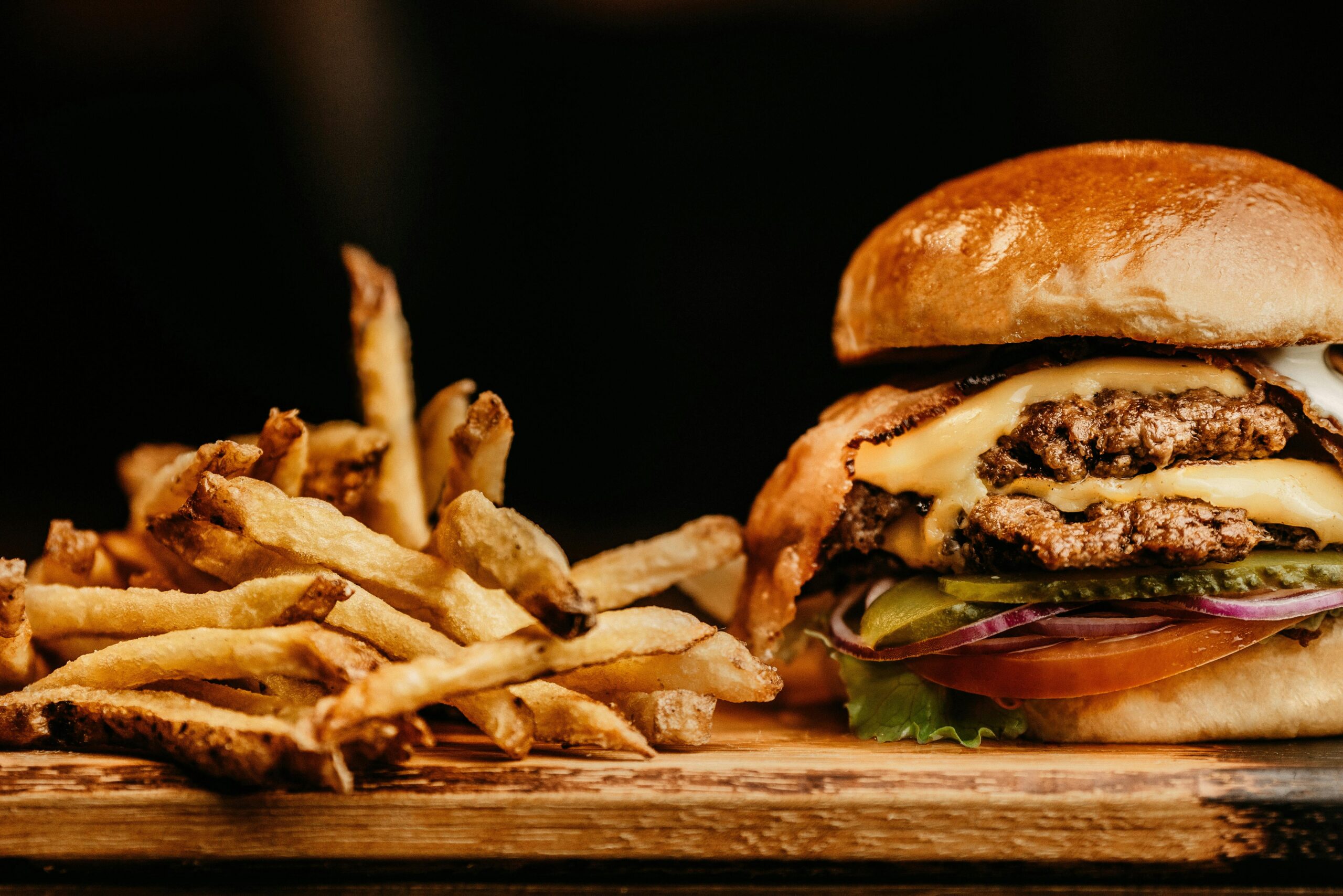 Cheeseburger with pickles, tomato, onion, and lettuce on a bun served with French fries.
