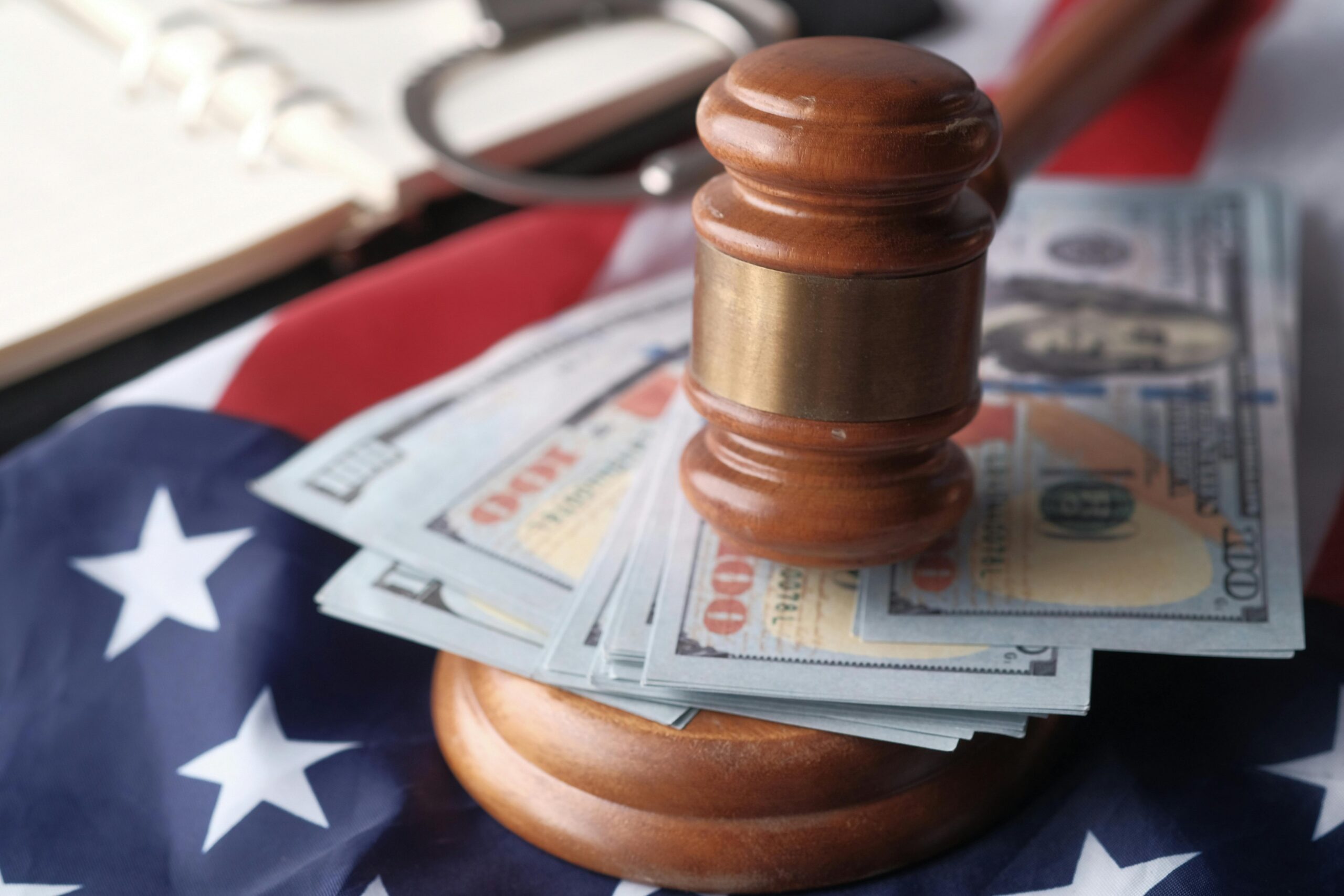 Judge’s gavel resting on US dollar bills placed over an American flag.