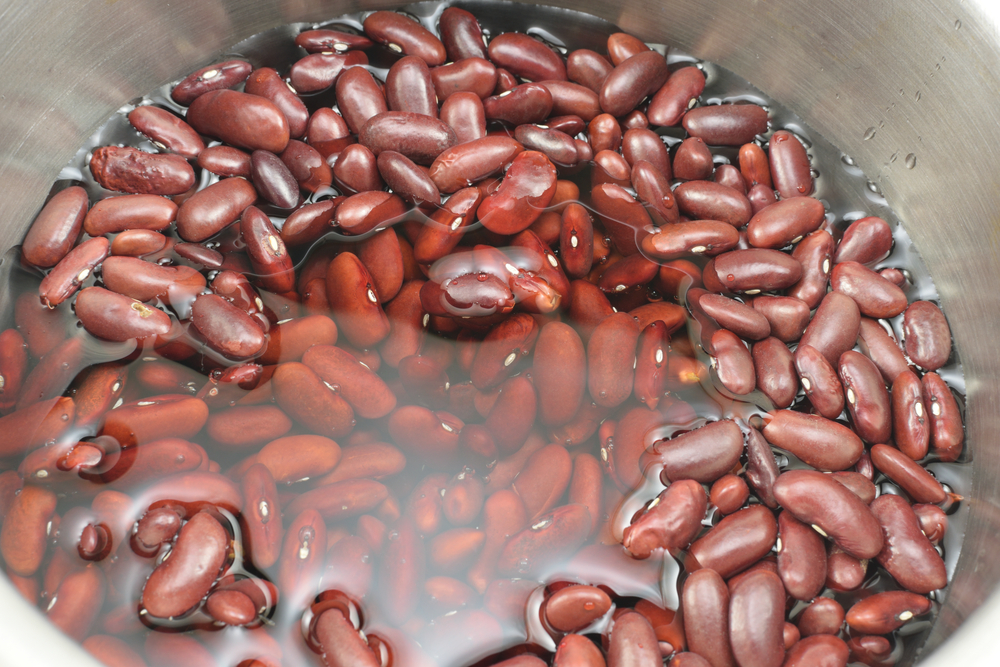 Red kidney beans soaking in water inside a stainless pot.