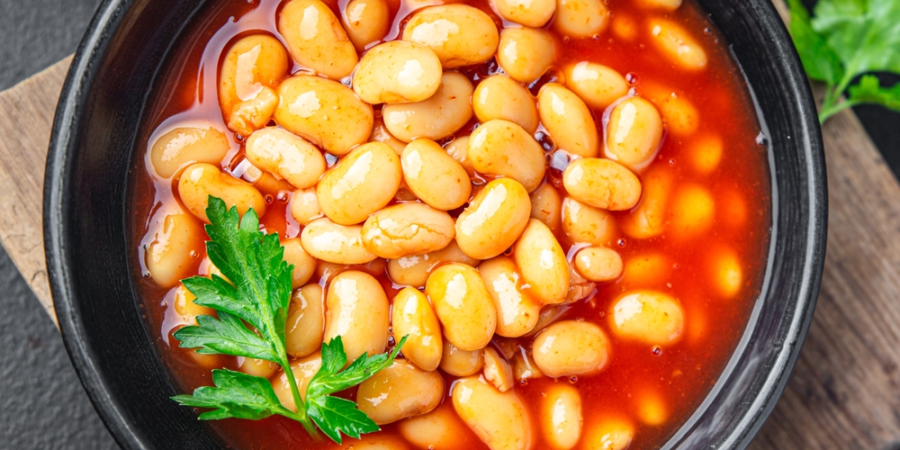 Bowl of baked beans in tomato sauce topped with fresh parsley garnish.