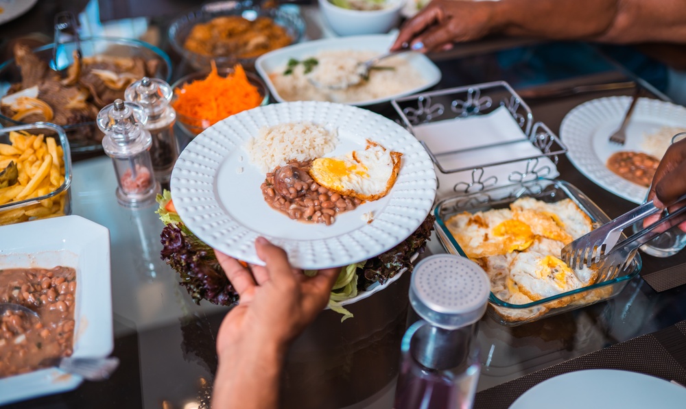 Plate of rice, beans, and fried egg being served from a table of home-cooked dishes.