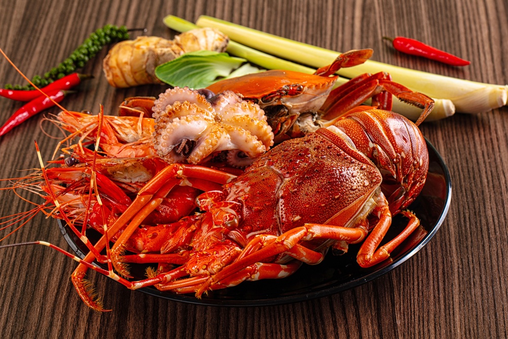 Platter of cooked seafood including lobster, crab, and octopus.