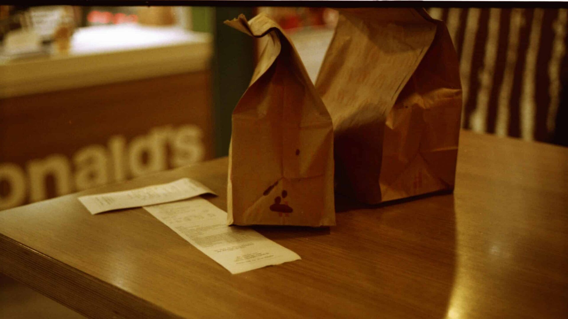 McDonald's paper takeout bag on wooden table in restaurant setting.