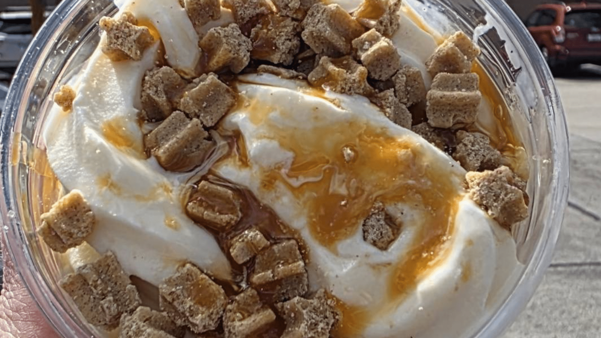A top-down close-up view of the Caramel Churro Sundae, showing the creamy white vanilla ice cream topped with a generous drizzle of salted caramel sauce.