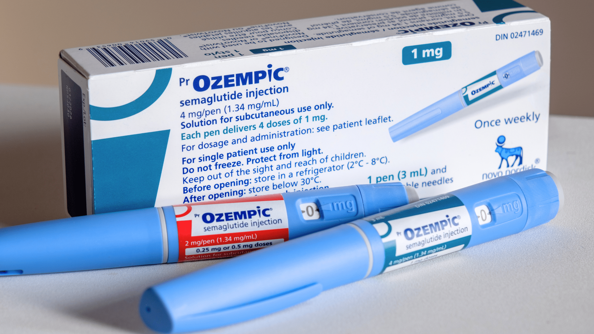 Two blue Ozempic injection pens lie next to their white and blue packaging box.