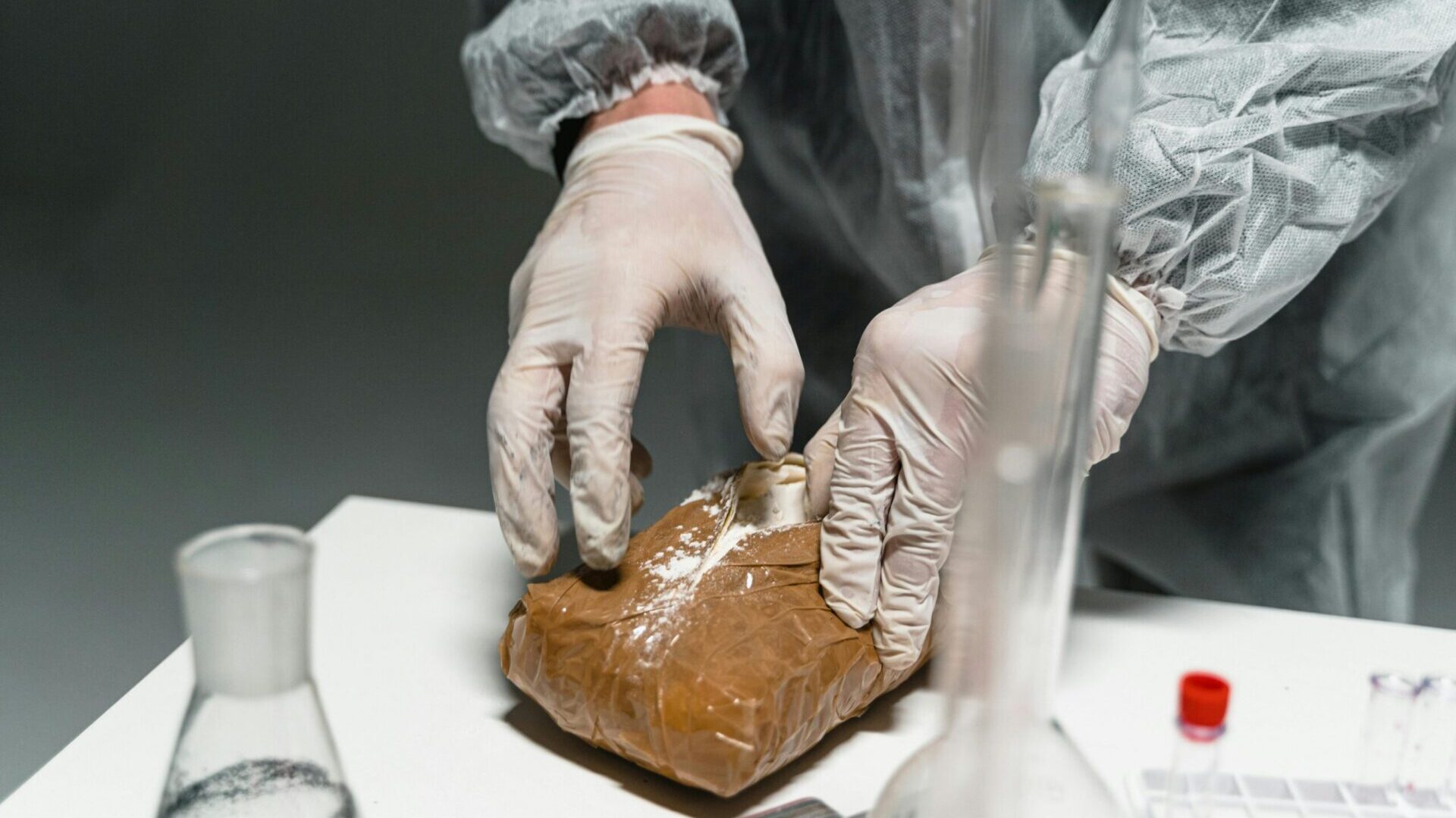 Gloved hands handling a packaged food item in a sterile laboratory setting.