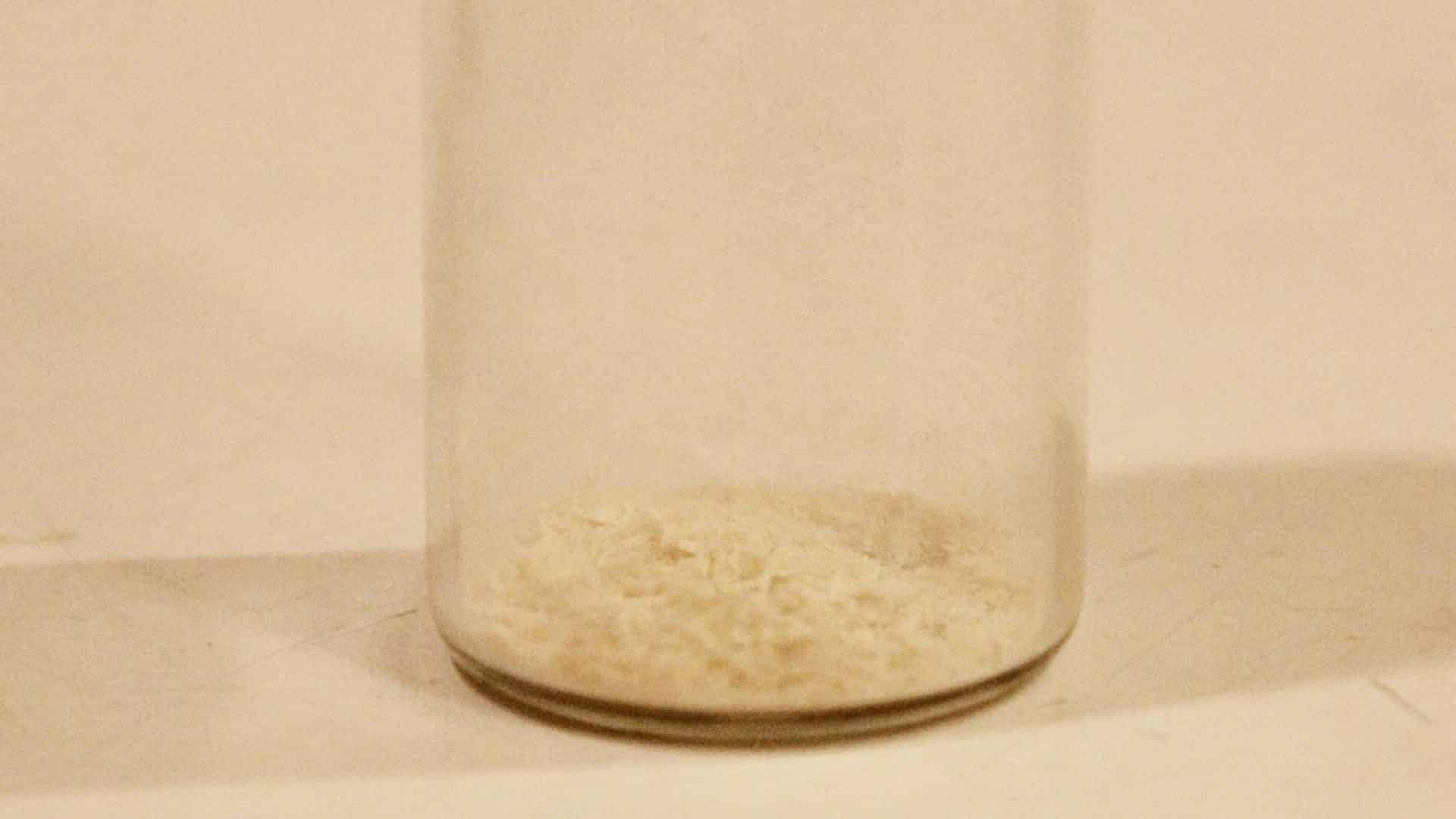 A glass jar containing a small amount of aspartame.