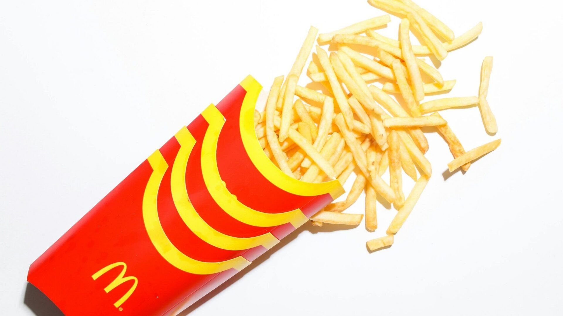 McDonald's French fries spilling out of a red and yellow branded container.