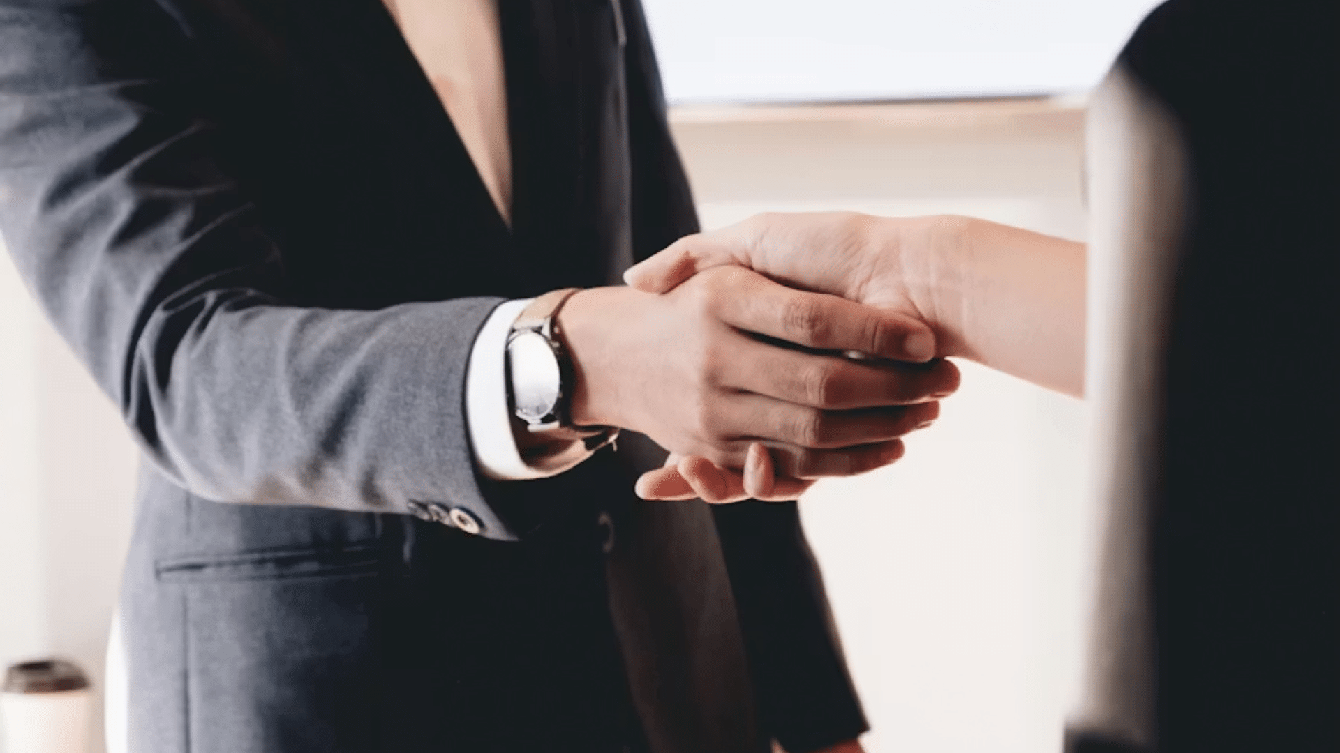 A close-up of a firm, professional handshake between two people in business suits, symbolizing a corporate agreement.