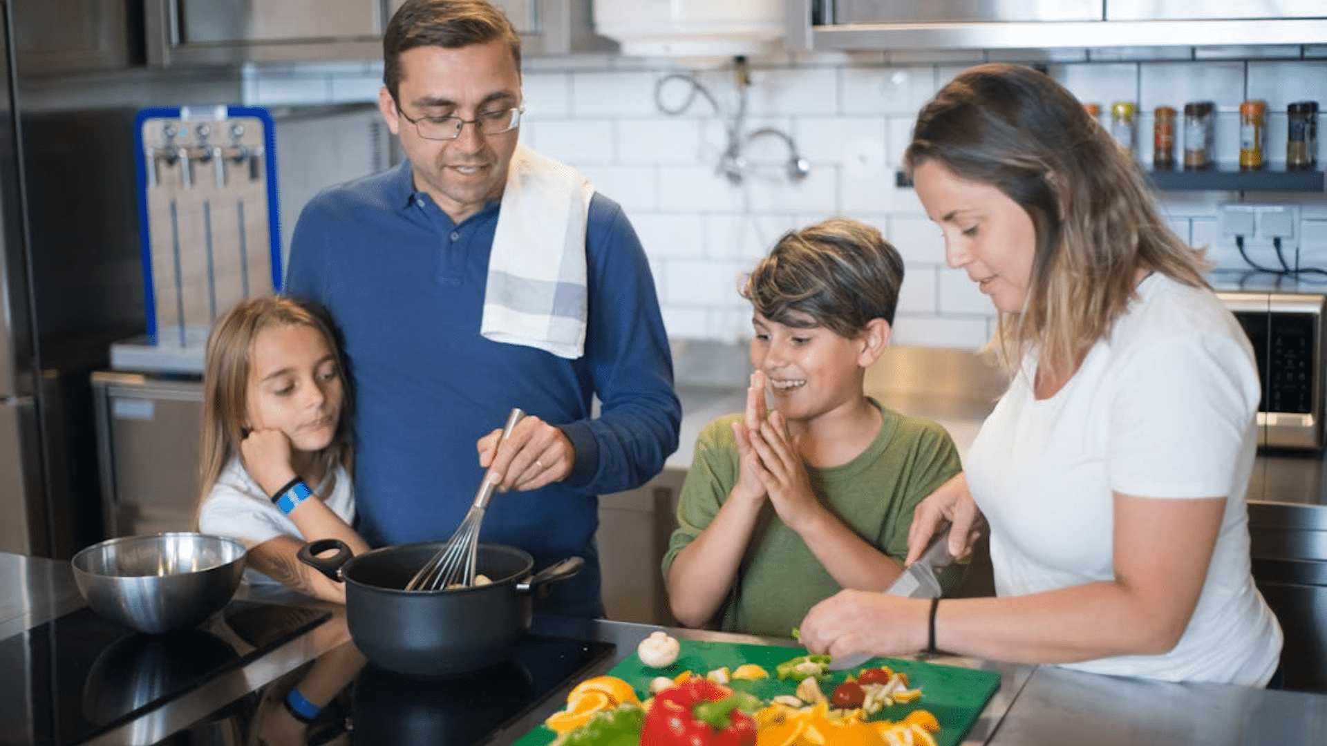 A family of four works together to cook a meal in a bright kitchen.