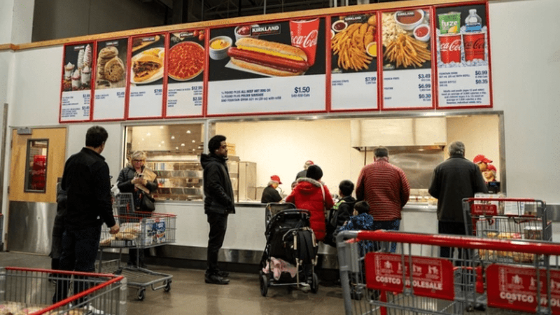 A wide shot of a busy Costco Food Court service counter with several customers in winter clothing waiting in line.