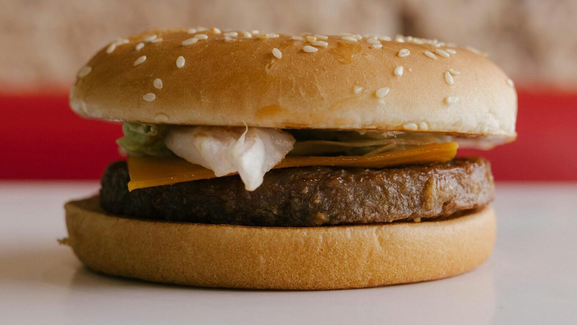 McDonald's hamburger with sesame seed bun, beef patty, and pickles on a plain background.