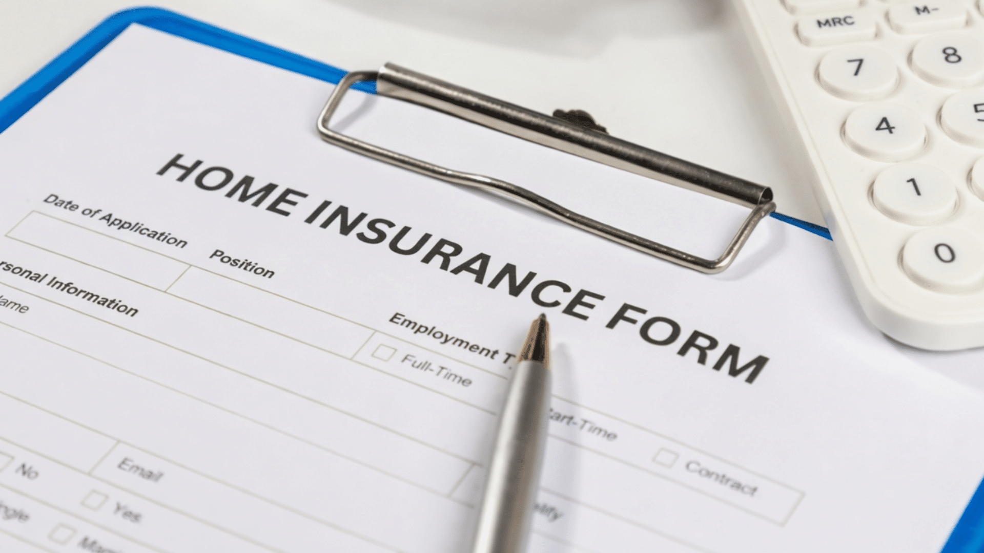 A home insurance form on a blue clipboard with a silver pen resting on the paper and a white calculator visible in the background.