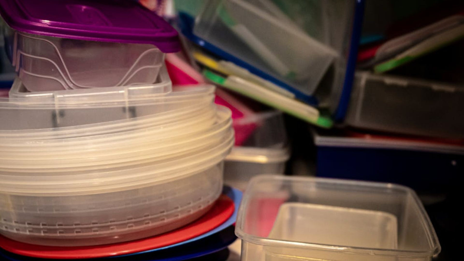 A pile of plastic containers with mismatched lids in various colors.