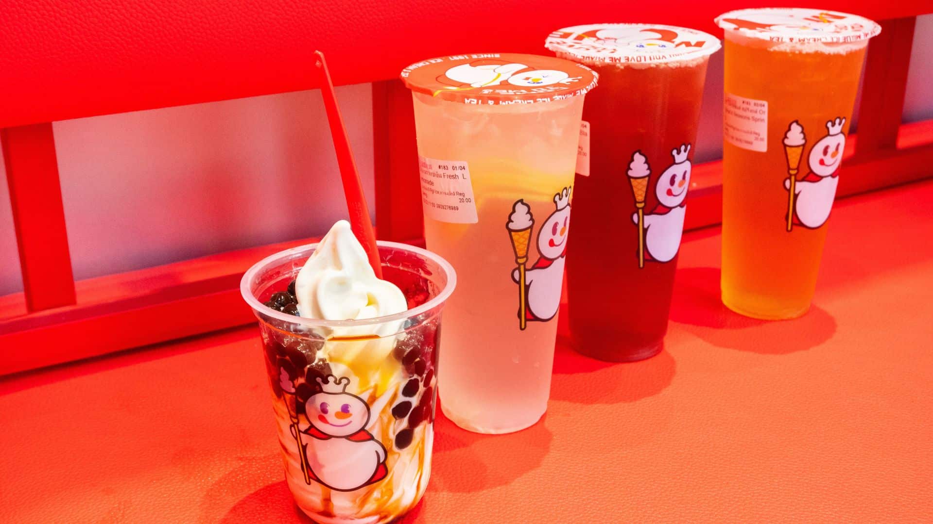 A cup full of soft-serve and boba lined up along a colorful set of other drinks from Mixue.