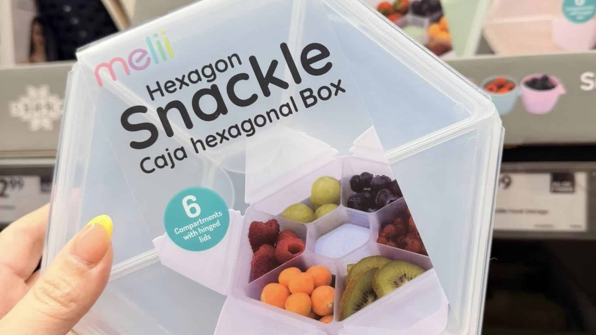 Hexagon snackle box with six compartments displayed in retail packaging with fruit shown inside sections.
