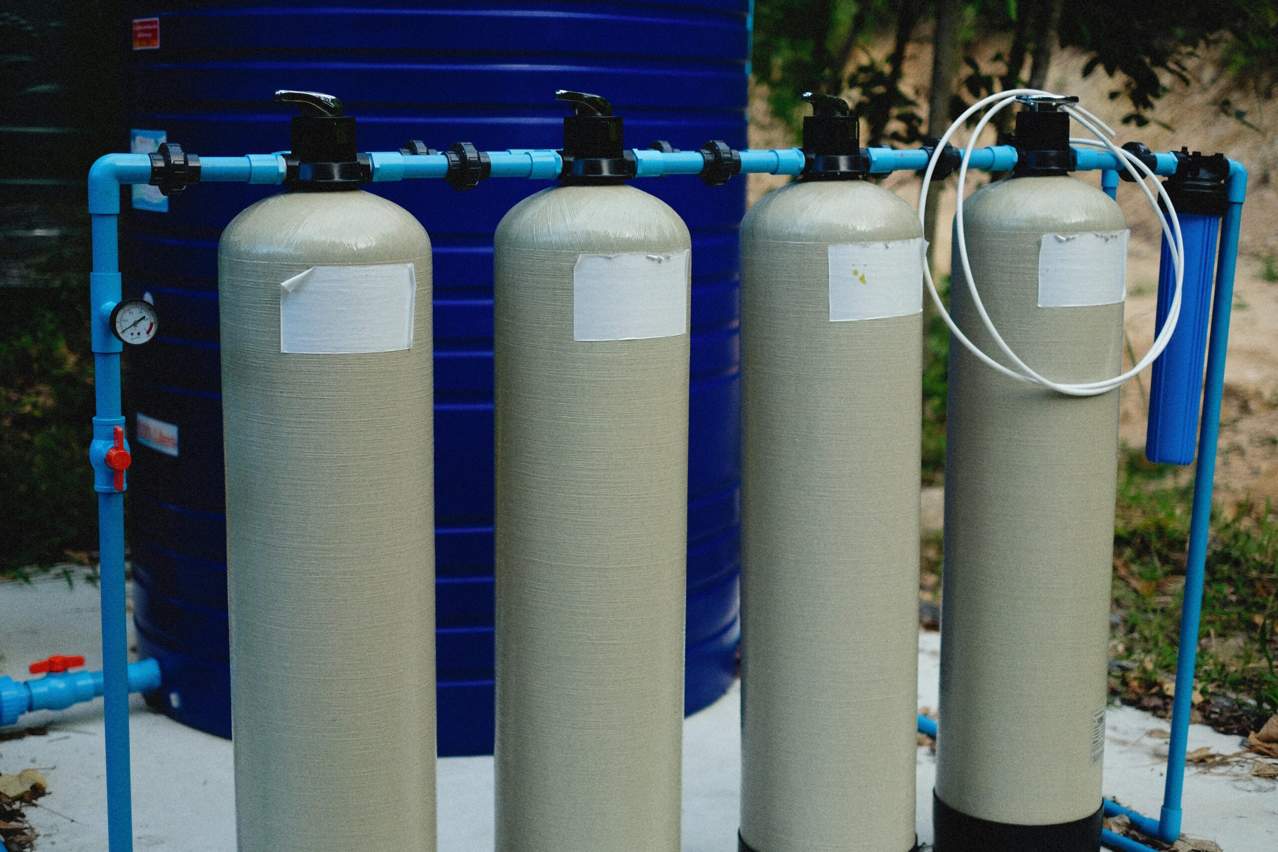 Outdoor water filtration system with multiple tanks connected to pipes and a large storage container.