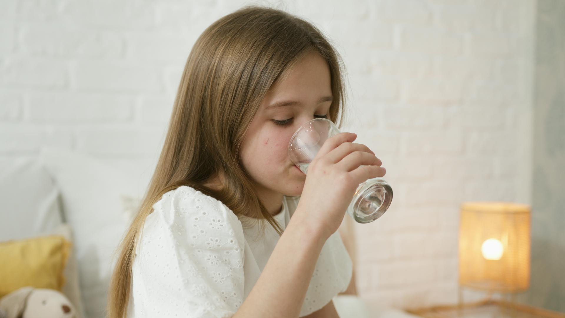 Young girl drinking water from a glass.