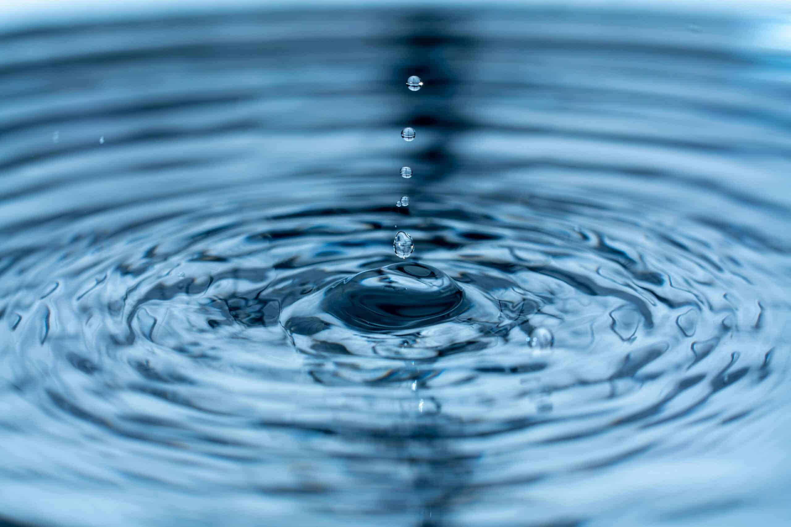 Water droplets falling into a surface, creating ripples and a small splash.