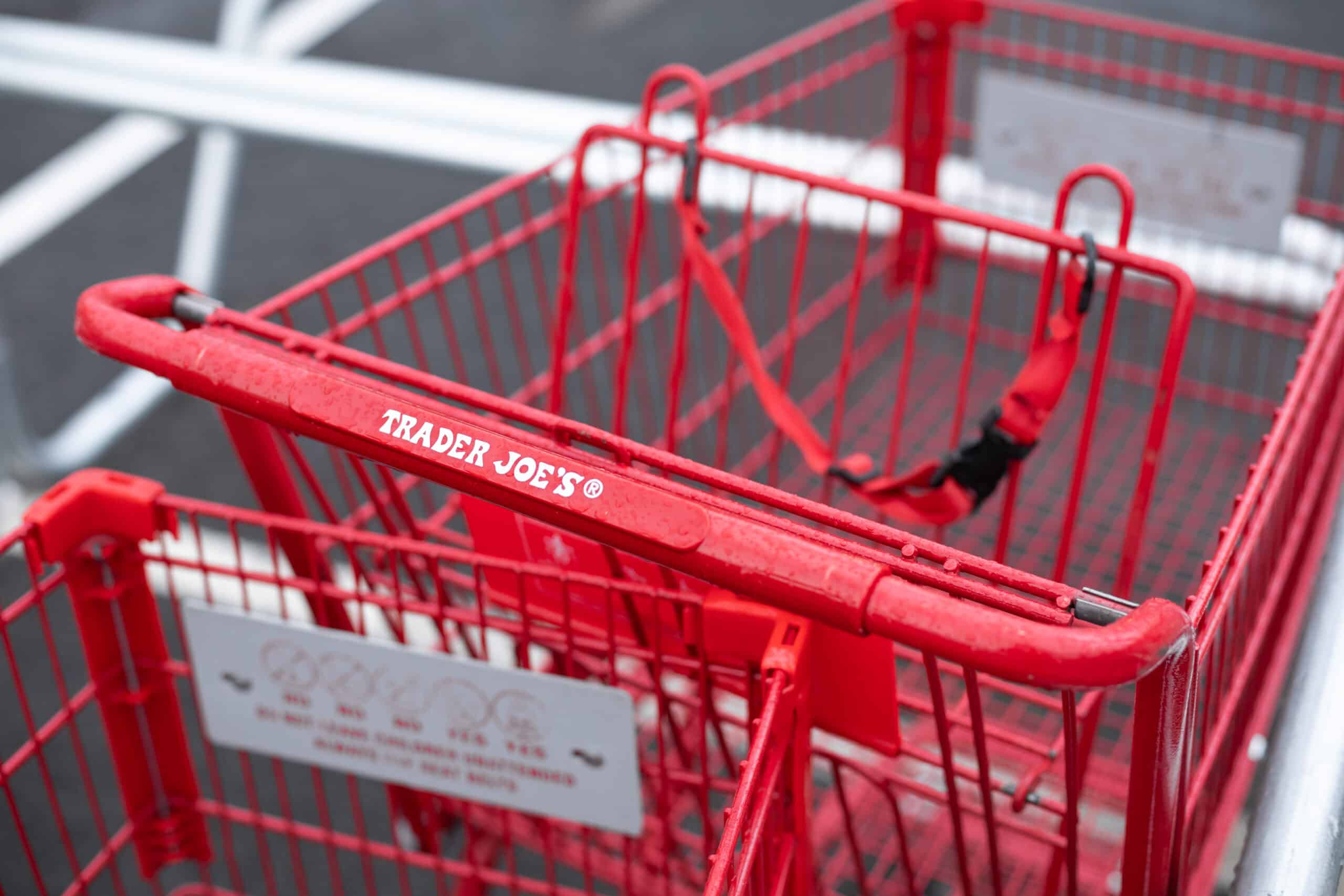 Red Trader Joe’s shopping cart in a parking lot with white painted lines.