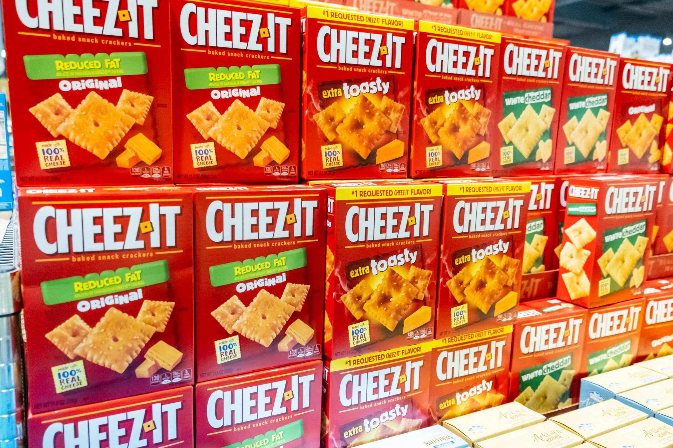 Cheez-It cracker boxes in multiple flavors stacked on a grocery store display shelf.