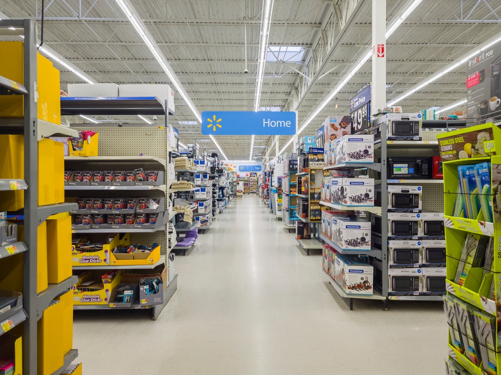 Walmart store aisle with shelves of household goods and overhead Home section sign.