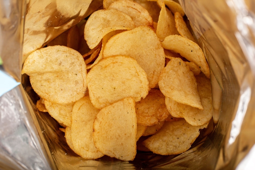 Open bag of Lay's potato chips showing seasoned chips inside foil packaging.