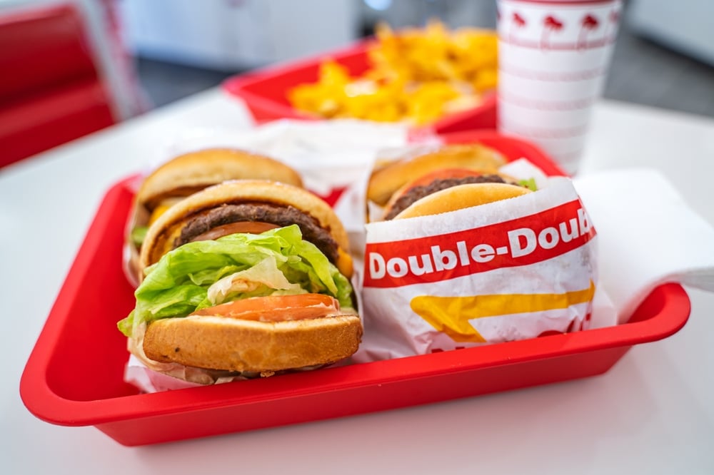 In-N-Out Burger meal with burgers, fries, and drinks served on red trays.