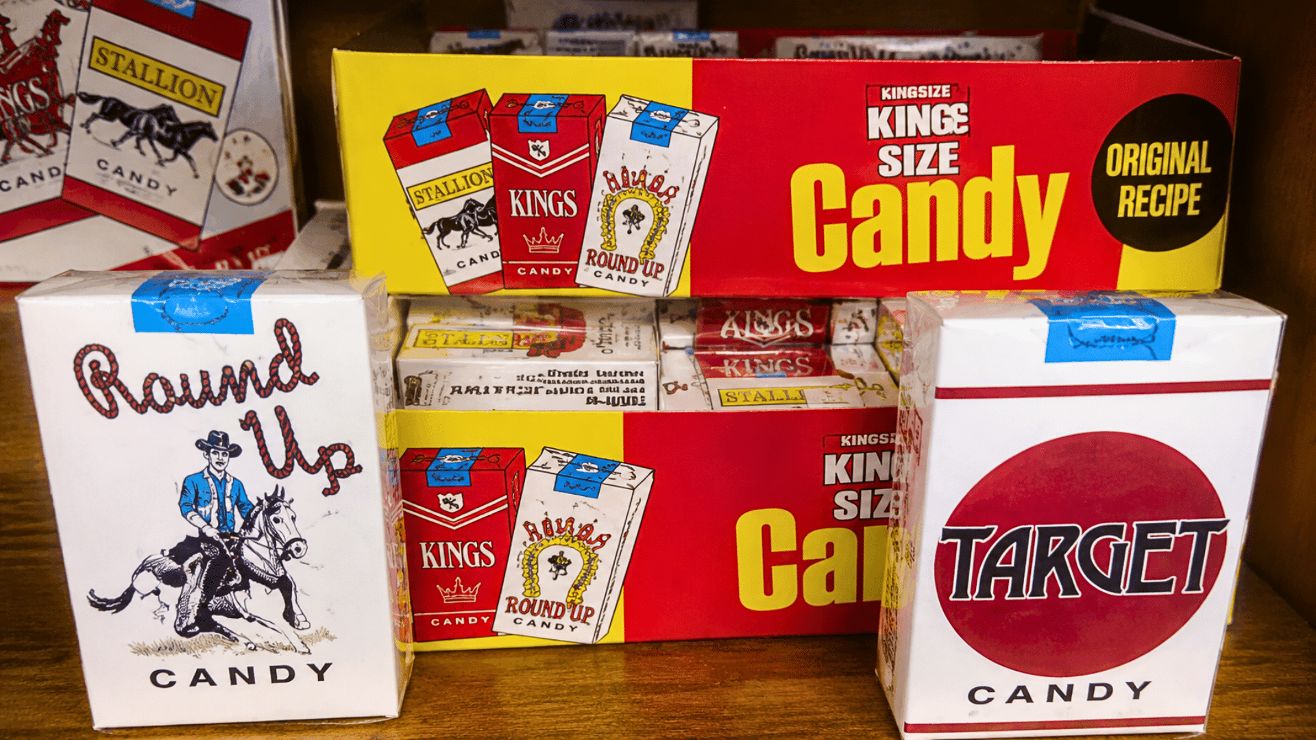 Candy cigarette boxes displayed on a wooden shelf.