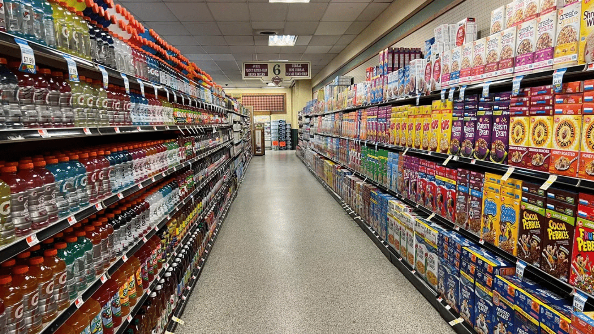 A perspective shot looking down a brightly lit, clean grocery store aisle.