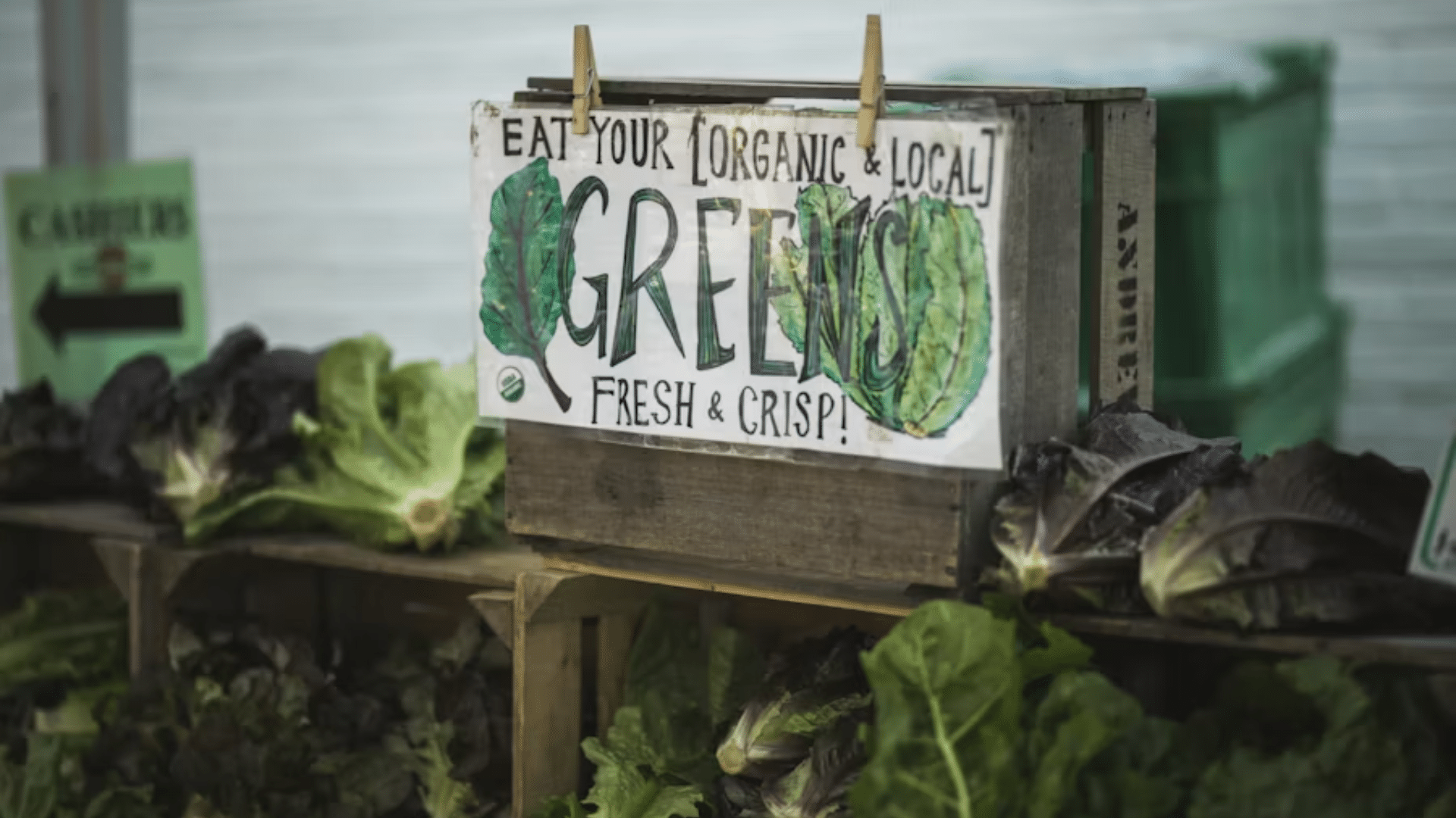 A close-up of a rustic wooden crate at a farmers' market with a hand-painted sign.