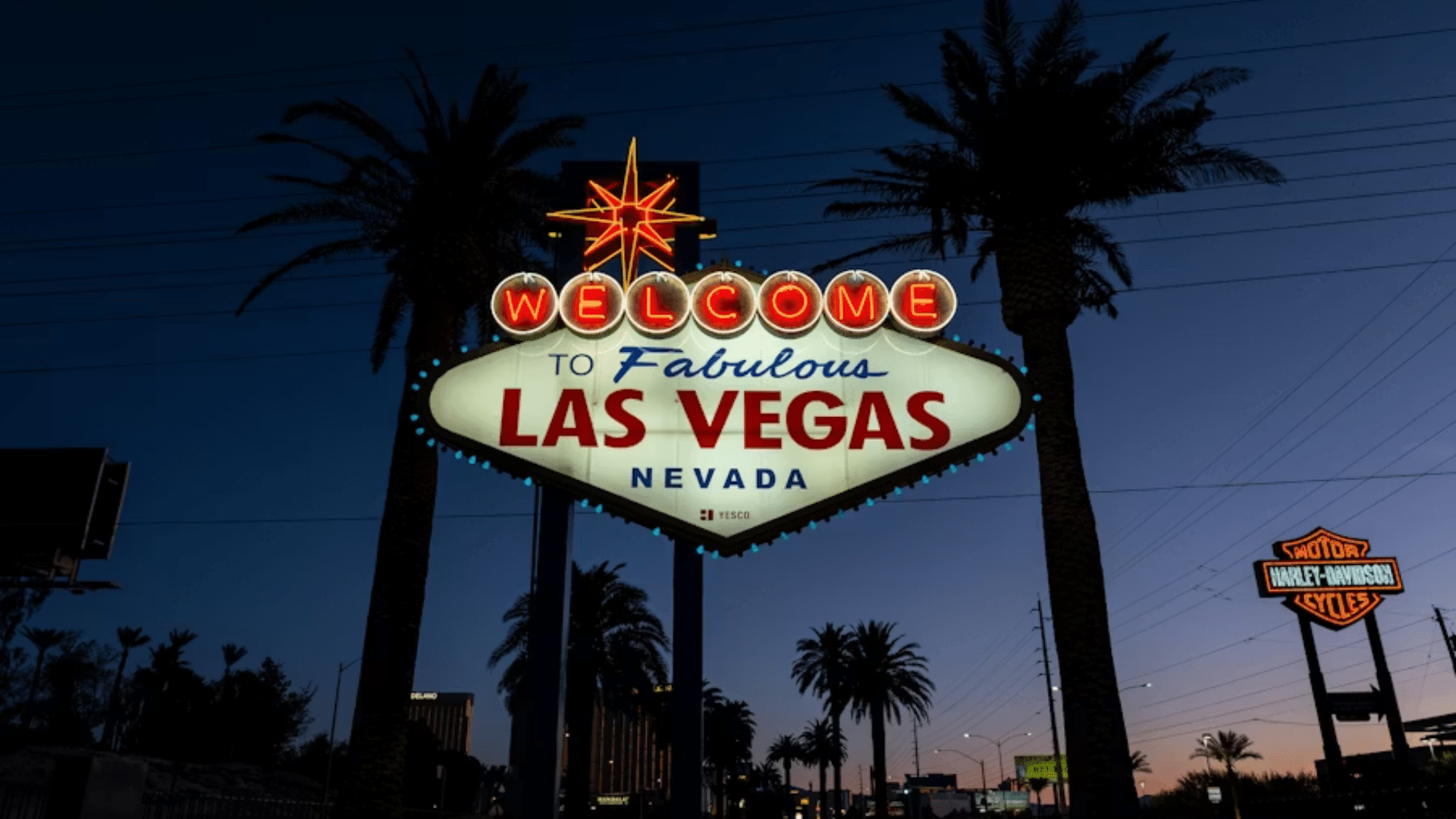 Welcome to Fabulous Las Vegas sign lit up at dusk with palm trees nearby.