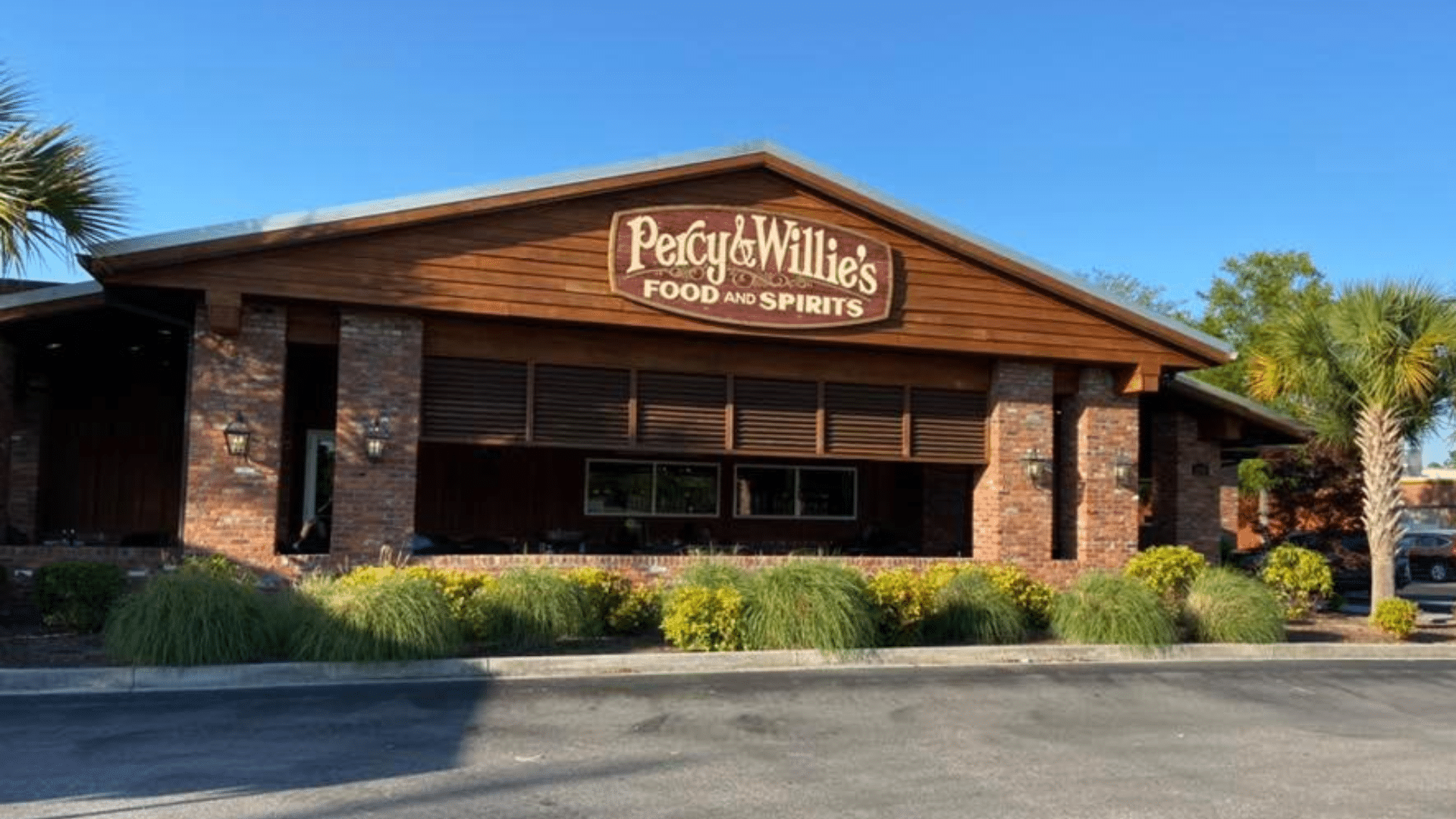 The exterior of a brick and wood restaurant named Percy & Willie's Food and Spirits on a sunny day.