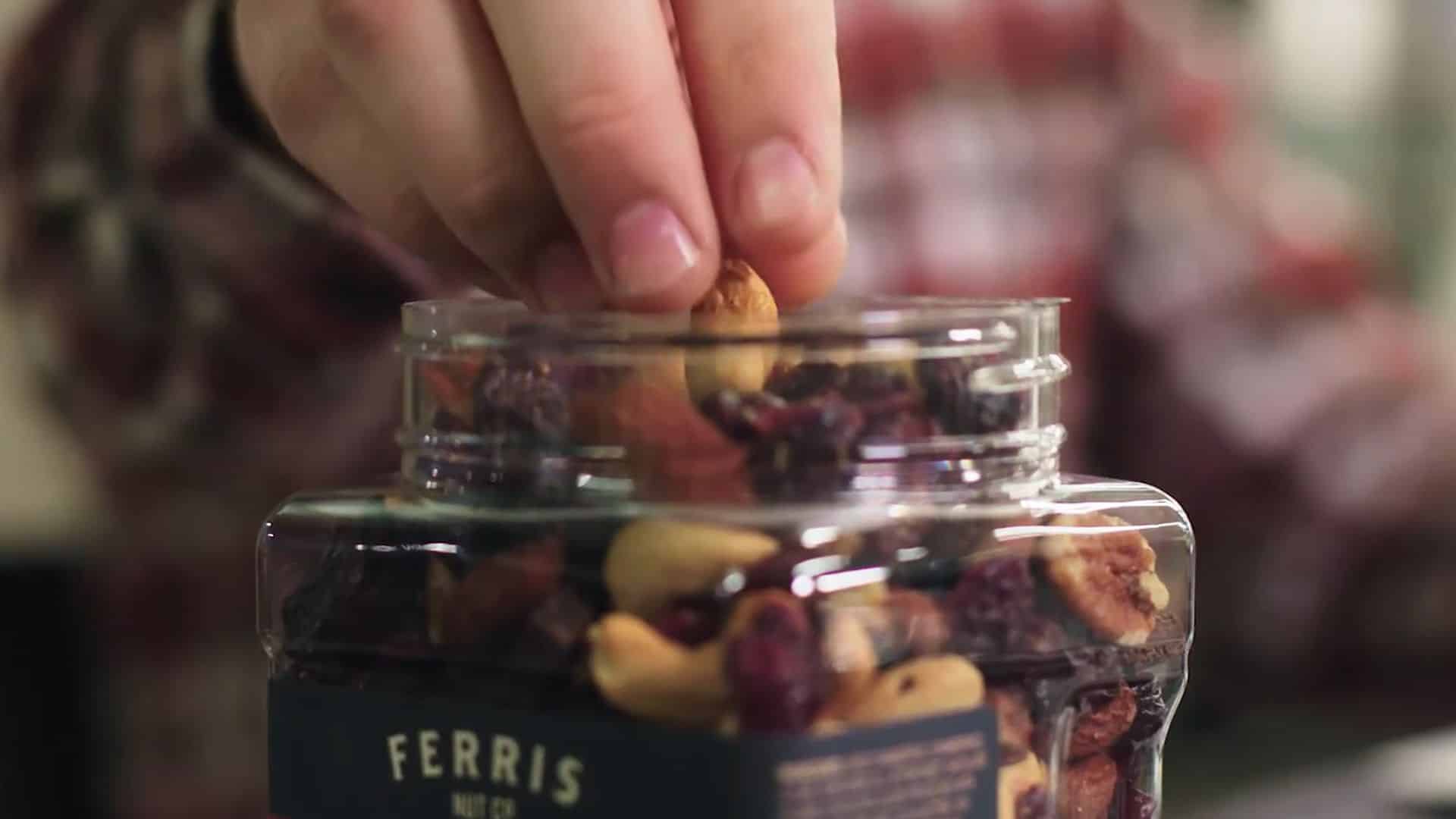 Hand reaching into a container of trail mix snacks.